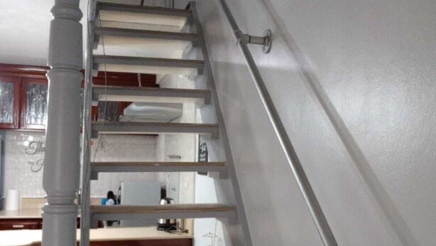 A staircase with a handrail, wooden steps, and a white wall. - Cozy Studio with Loft WiFi and AC in New Kingston (Kingston)