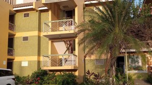A multi-story building with balconies, a palm tree, and a car parked in front. - Cozy Studio with Loft WiFi and AC in New Kingston (Kingston)