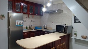 A kitchen with a refrigerator, microwave, sink, and wooden cabinets. - Cozy Studio with Loft WiFi and AC in New Kingston (Kingston)