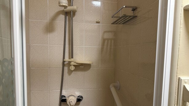 A shower with a handheld showerhead, a handheld showerhead, and a handheld showerhead.