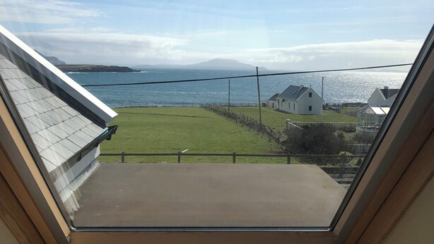 A skylight with a view of a grassy area, a body of water, and distant hills. - Spacious 5-bedroom house with sea views for up to 12 guests in beautiful Achill (Dooagh, Achill Island)
