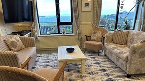 A living room with a view of the sea, featuring striped sofas, a coffee table, and a patterned rug. - Spacious 5-bedroom house with sea views for up to 12 guests in beautiful Achill (Dooagh, Achill Island)