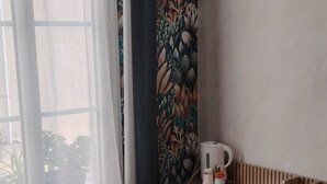 Una stanza con una scrivania in legno, una sedia, una finestra con tende e un muro decorato.