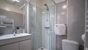Un bagno moderno con box doccia in vetro, un water e un lavandino con specchio sopra.