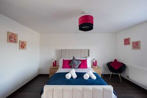 A bedroom with a bed, nightstands, a chair, and artwork on the walls.