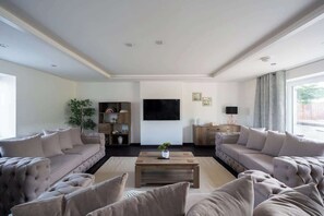 A spacious living room with two sofas, a coffee table, a TV, and a bookshelf.
