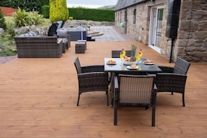 A patio with wicker furniture, a table set with plates, glasses, and a pineapple.