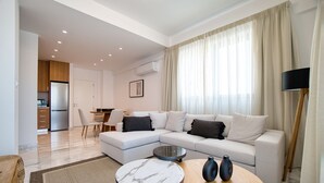 A modern living room with a sectional sofa, a dining table, and a kitchen area in the background.