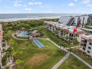 Un complexe hôtelier doté d’une piscine, de palmiers et offrant une vue sur la plage.