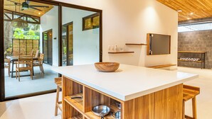 Une cuisine moderne dotée d’un grand îlot central, de meubles en bois et offrant une vue sur un espace de repas extérieur.