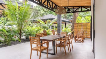 Enjoy a dining experience surrounded by lush greenery and a wooden roof structure.