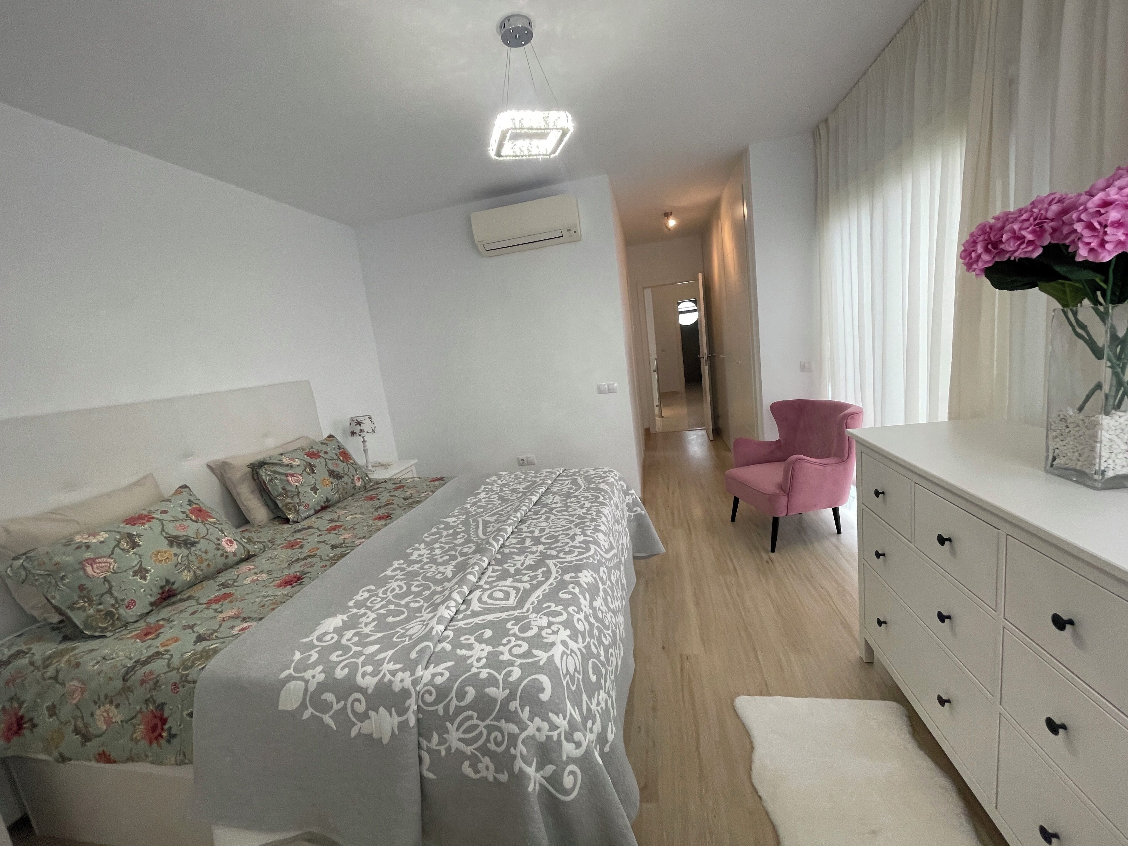 Quarto com uma cama, cômoda, cadeira e mesa de cabeceira.