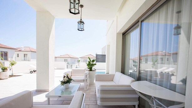 Un espace de vie extérieur moderne, comprenant un canapé, des fauteuils, une table basse et une plante en pot.
