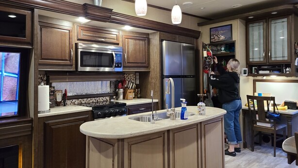 A modern kitchen with wooden cabinets, stainless steel appliances, and a central island. - Cozy RV with WiFi and HVAC in Glendale/North Phoenix Luxury Fifth wheel camper (Glendale)