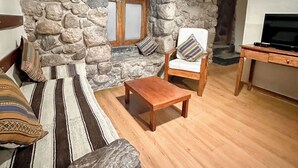 Een gezellige woonkamer met een stenen muur, een houten salontafel, een bank en een tv-meubel.