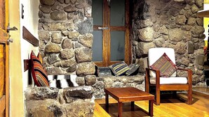 Una habitación con paredes de piedra, una puerta de madera, una pequeña mesa de madera y una silla con cojín.