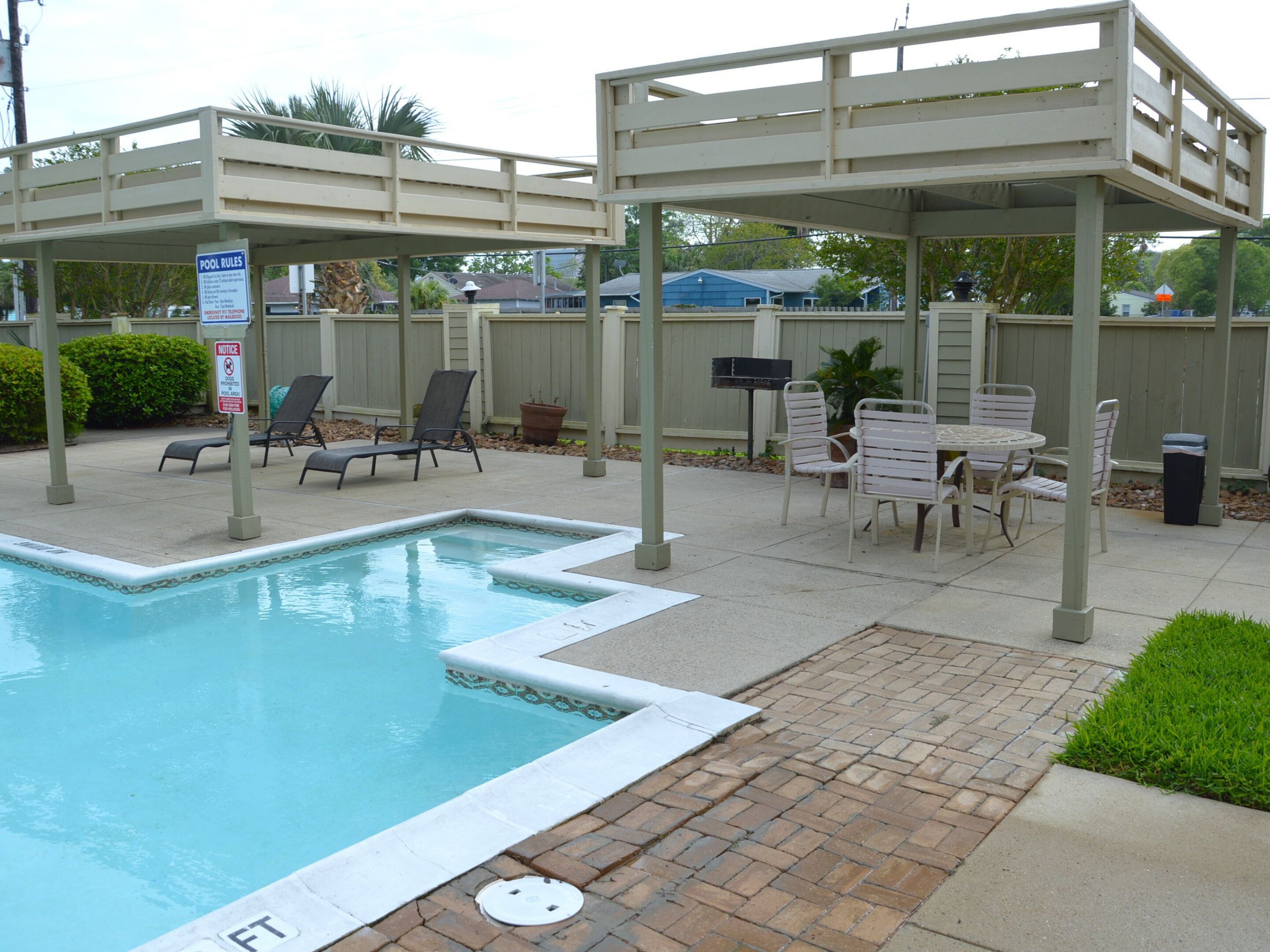 Una piscina con sillones de descanso y un área de patio techada.