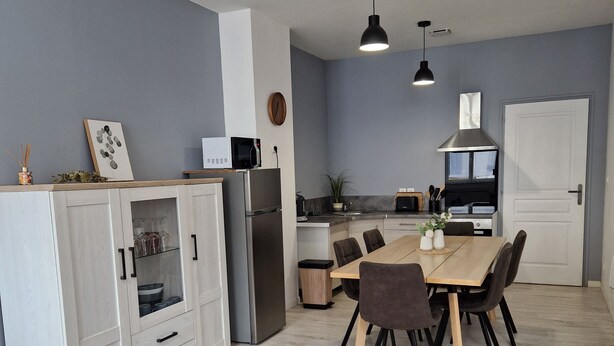 Una cocina moderna con comedor, sofás grises y un armario blanco.
