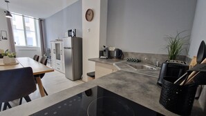 Una cocina moderna con estufa integrada, refrigerador y pileta. Hay una zona de comedor con mesa y sillas.