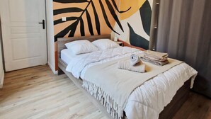 Un dormitorio con cama, un mural en la pared, una puerta y un ventanal con cortinas.