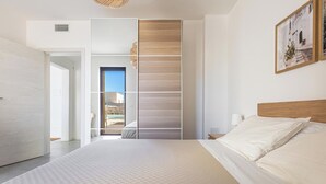 A modern bedroom with a large bed, a built-in wardrobe, and a view of the outdoors. - Villa Li Santi - 2 by BarbarHouse (Santa Caterina)