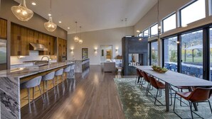 Een moderne keuken met een marmeren eiland, houten kasten en hanglampen.