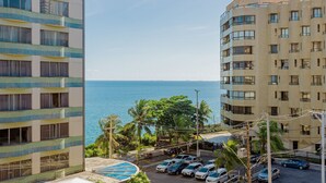 A high-rise building with multiple balconies and a view of the sea.