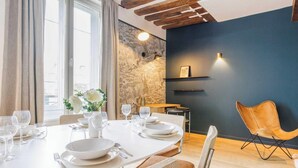 A dining area with a white table set for four, a vase of white flowers, and a blue accent wall. - NESTLED IN THE LIVELY AND CHARMING NOTRE-DAME-DES-CHAMPS DISTRICT- RUE DE SEVRES (Paris)