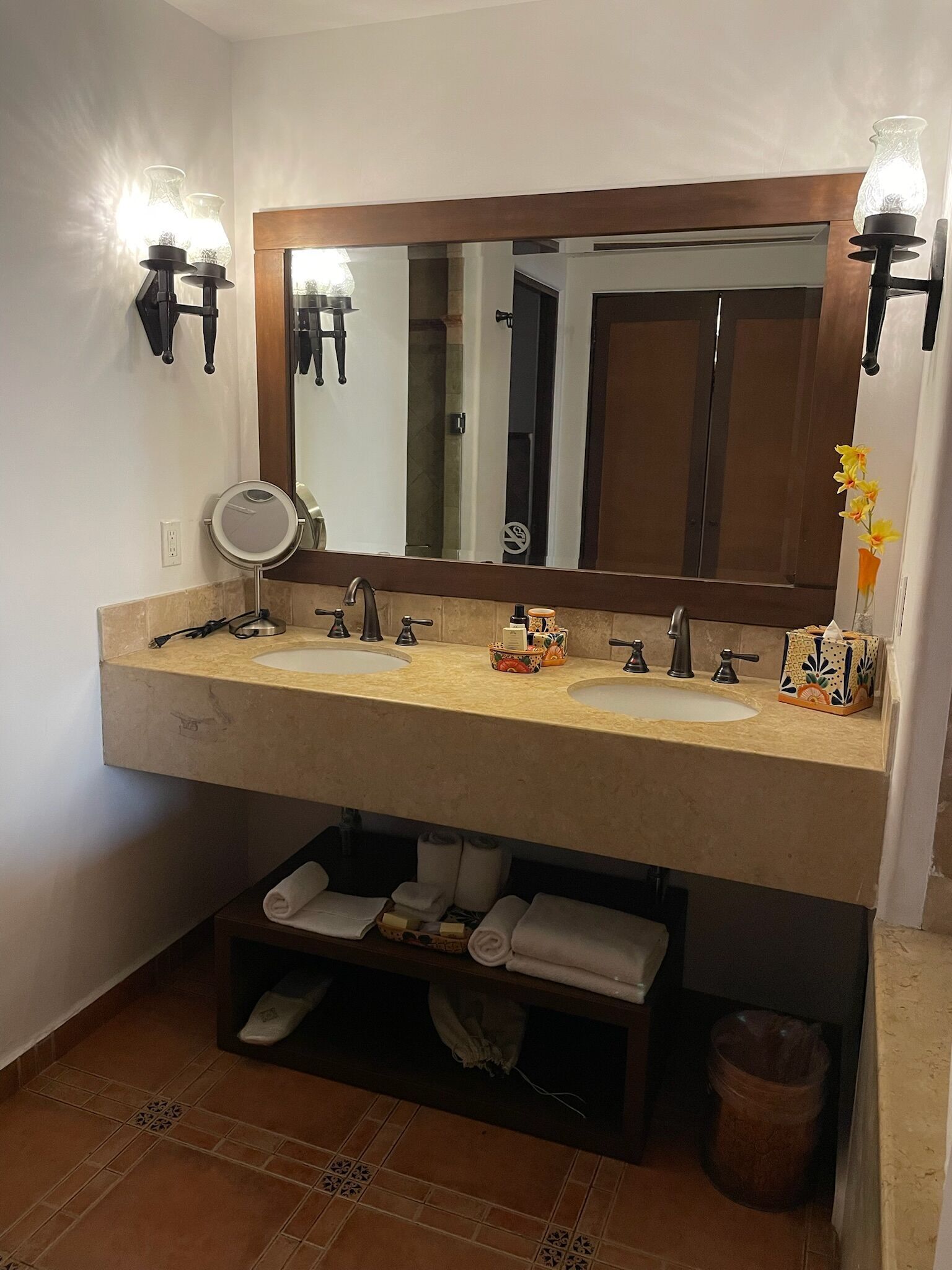 A bathroom with a double sink, a round mirror, and a vanity with a towel rack.
