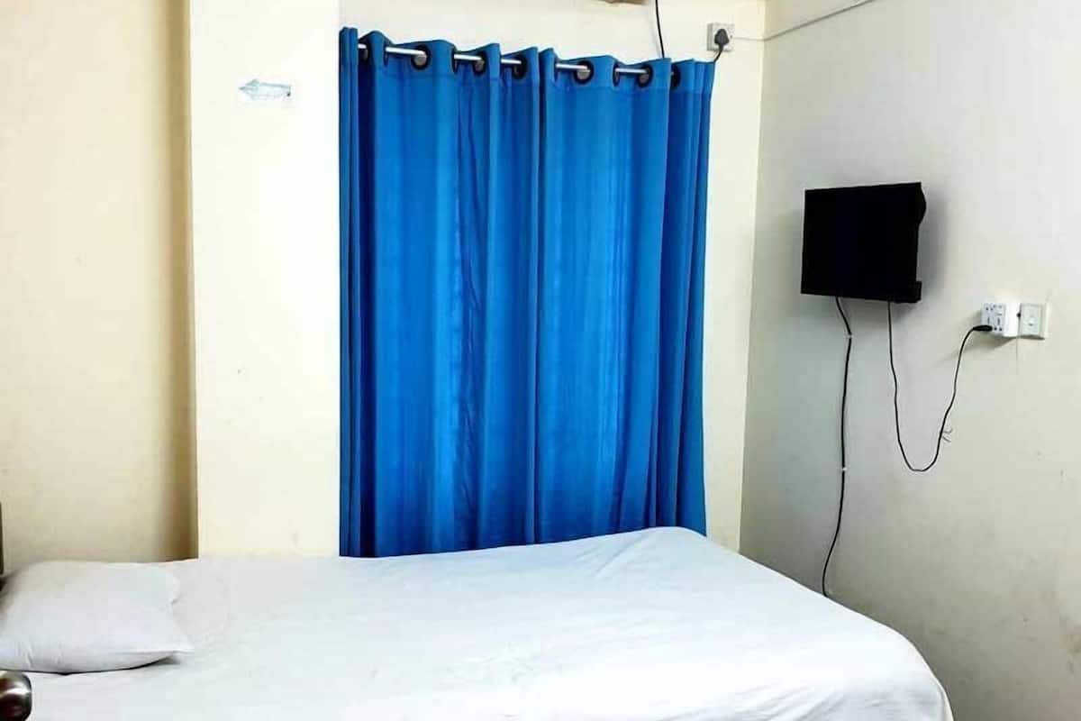 Un lit simple avec un matelas blanc et un rideau bleu.