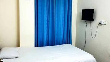 A single bed with a white mattress and a blue curtain.