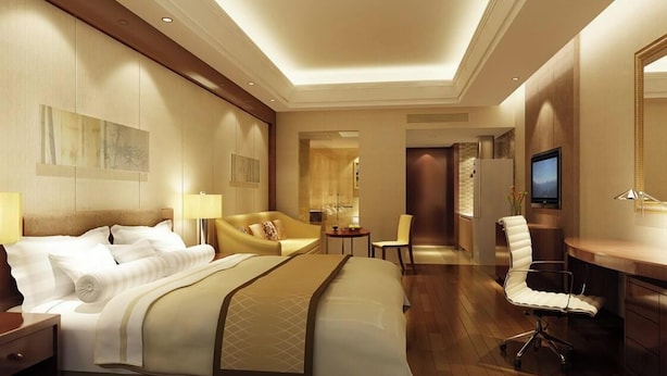 Una habitación de hotel con una cama grande, un escritorio, una silla, un televisor y una mesita.