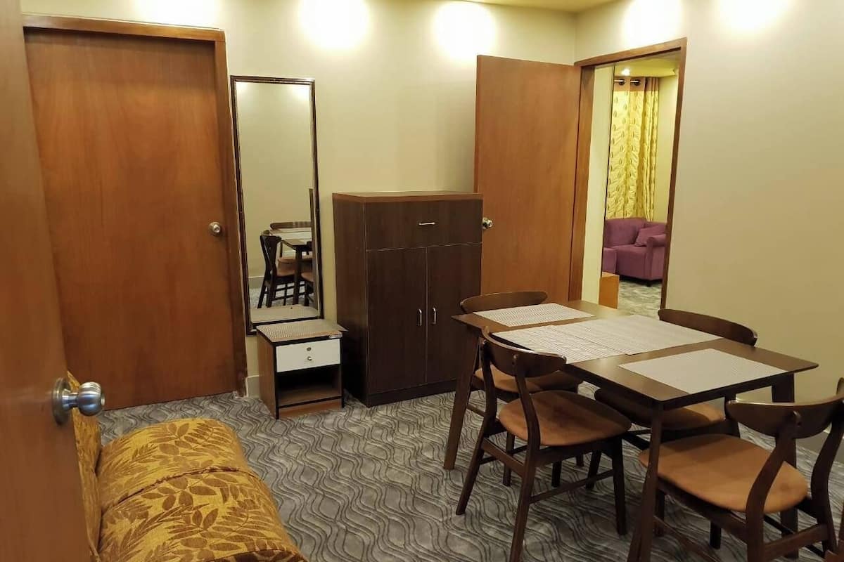 Une pièce de taille modeste comprenant un lit, une armoire, une petite table avec des chaises et un miroir.