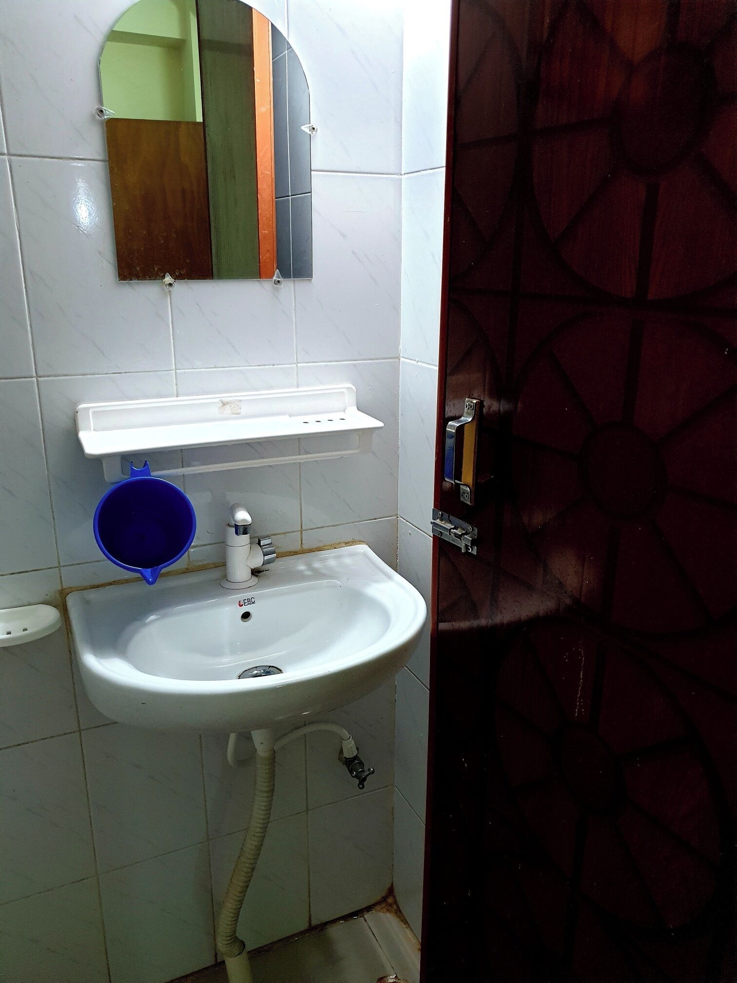 A bathroom with a white sink, a mirror, and a blue basin.