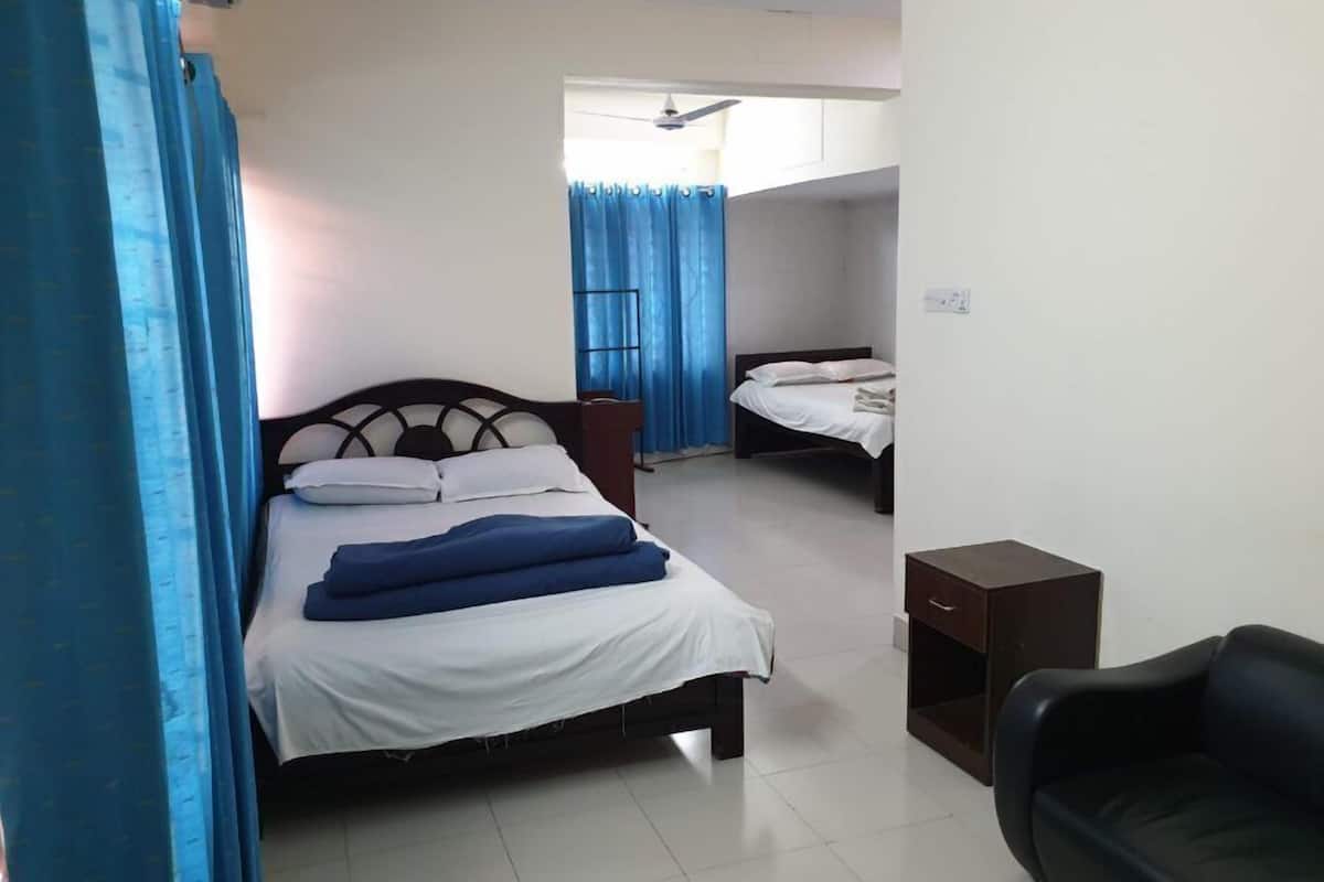 Une chambre d’hôtel avec un lit, une chaise, une petite table et une fenêtre avec des rideaux.