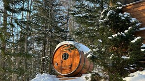 A wooden barrel-shaped structure in a snowy forest setting.