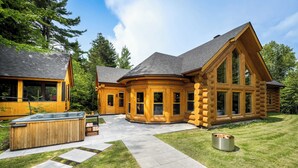 A log cabin with a hot tub, stone pathway, and a fire pit.