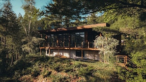 Een moderne houten chalet met grote ramen, omringd door dicht bos.
