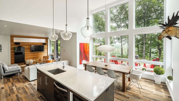 Cozinha moderna com ilha central, grandes janelas e área de refeições com vista para o exterior.