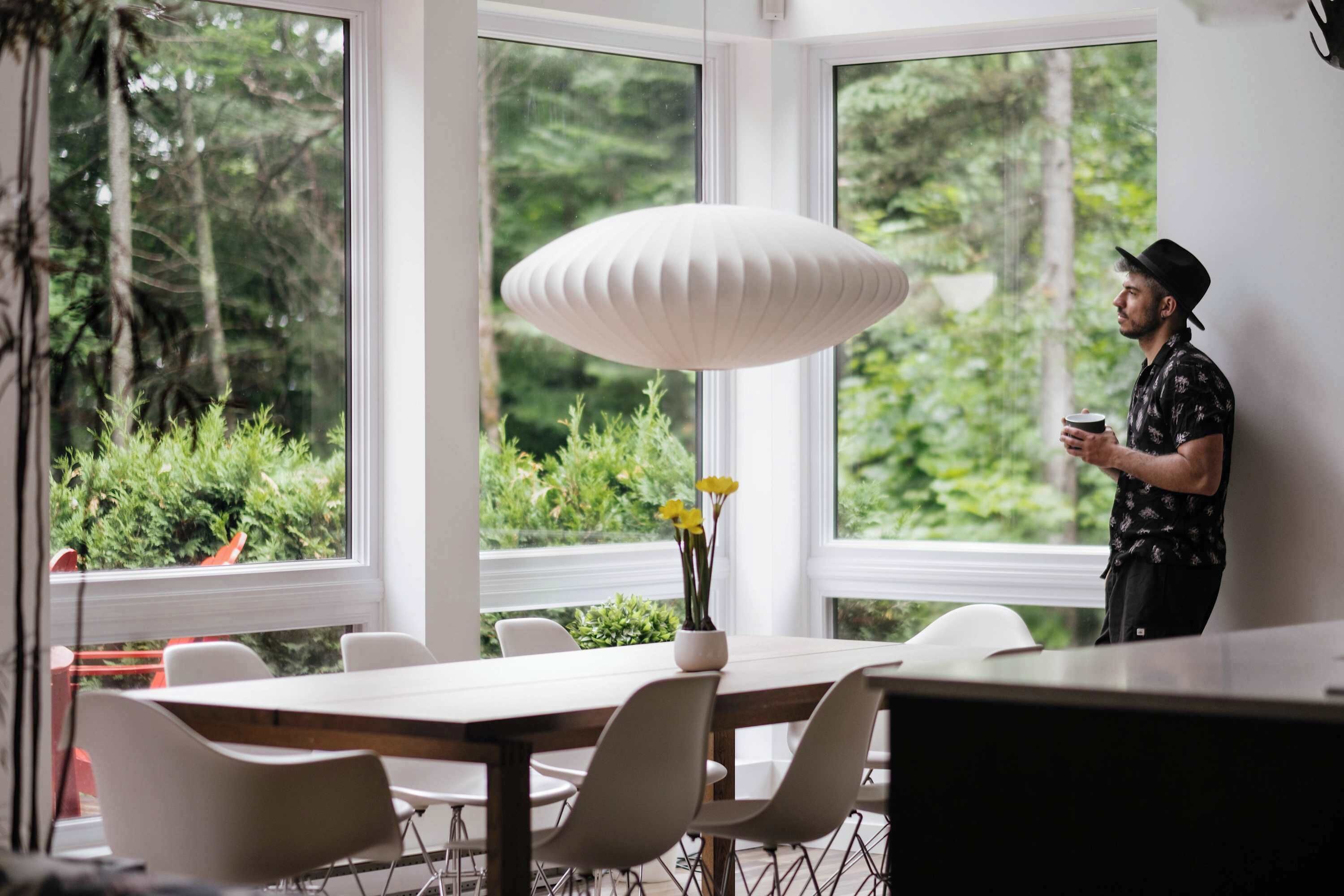 A modern dining area with a large window, a white pendant light, and a table with chairs.