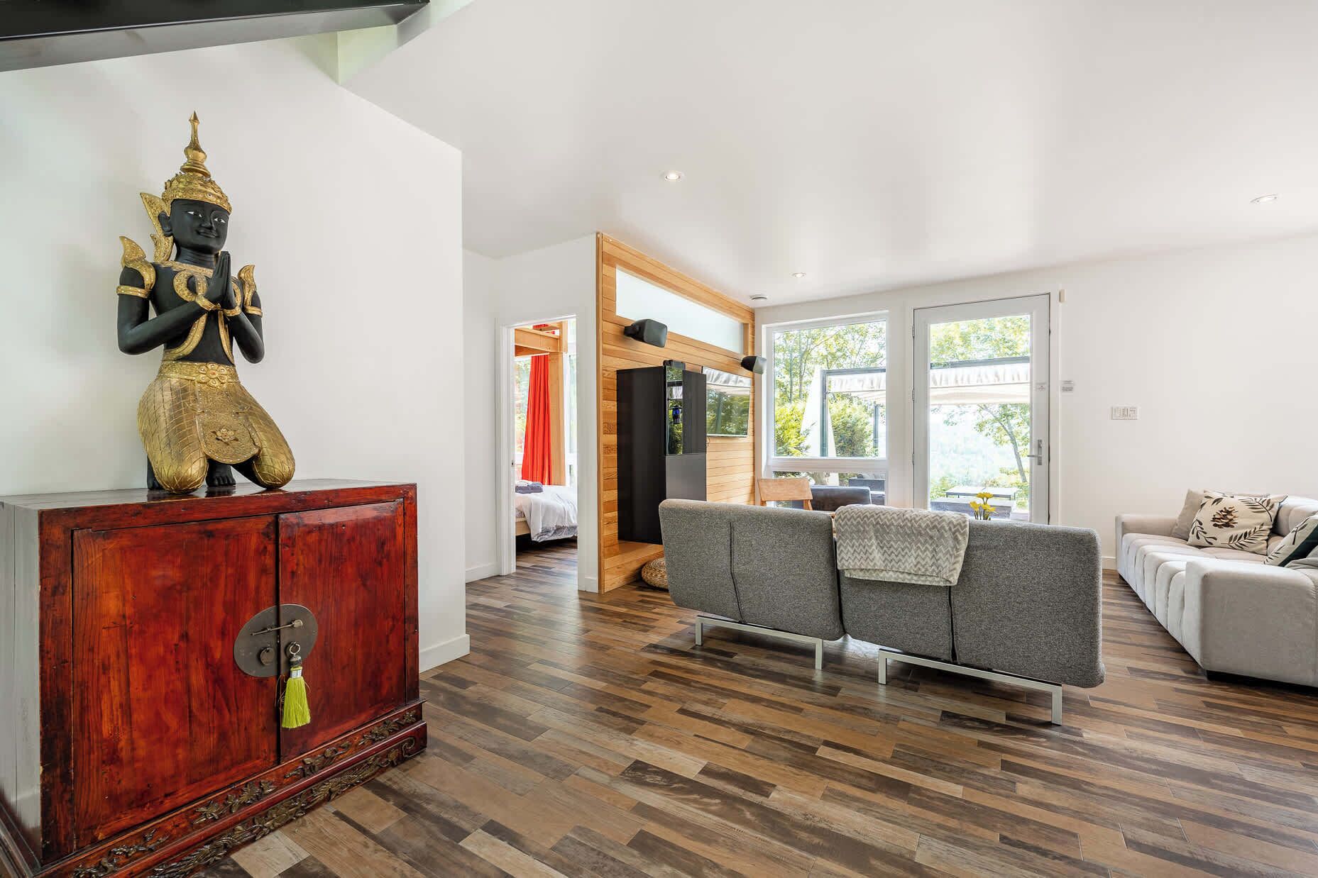 Un salon moderne avec un meuble en bois, un canapé et une statue.