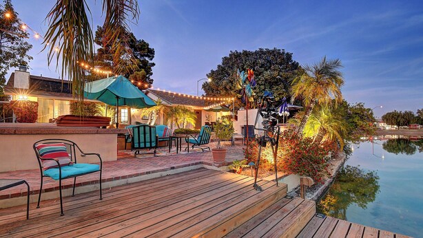 A wooden deck with outdoor seating, a pool, and string lights. - Mesa Lake Front House With Pool and Hot Tub! (Mesa)