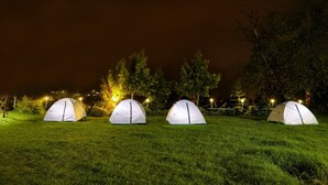 Three dome-shaped tents on a grassy field at night, illuminated by street lamps. - BRITISH CLIFF CLUB RESORT (Ootacamund)