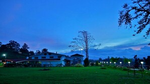 A large house with a garage and a covered porch, surrounded by a grassy yard and trees. - BRITISH CLIFF CLUB RESORT (Ootacamund)