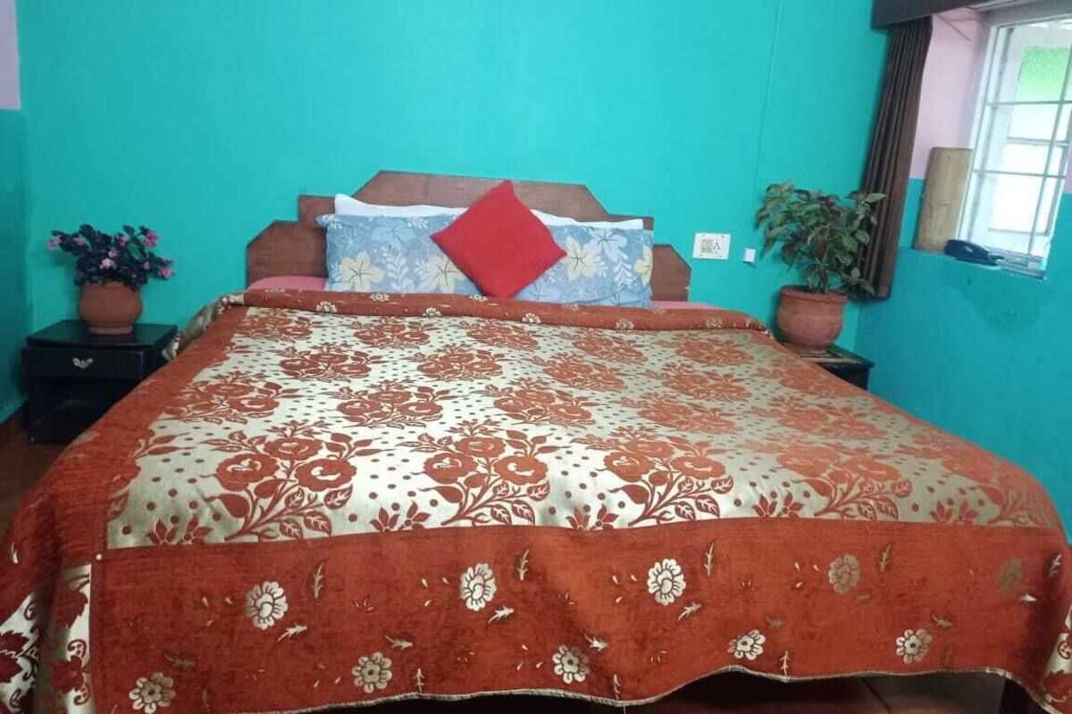 Une chambre à coucher avec un lit, deux tables de chevet, une fenêtre et une plante en pot.