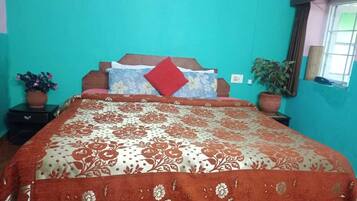 A bedroom with a bed, two nightstands, a window, and a potted plant.