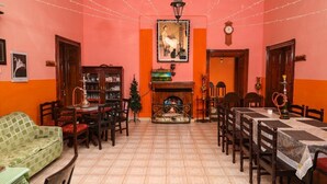 A dining area with a fireplace, wooden furniture, and a pink wall. - BRITISH CLIFF CLUB RESORT (Ootacamund)