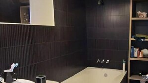 Une salle de bain moderne équipée d’une baignoire, de toilettes et d’un lavabo.