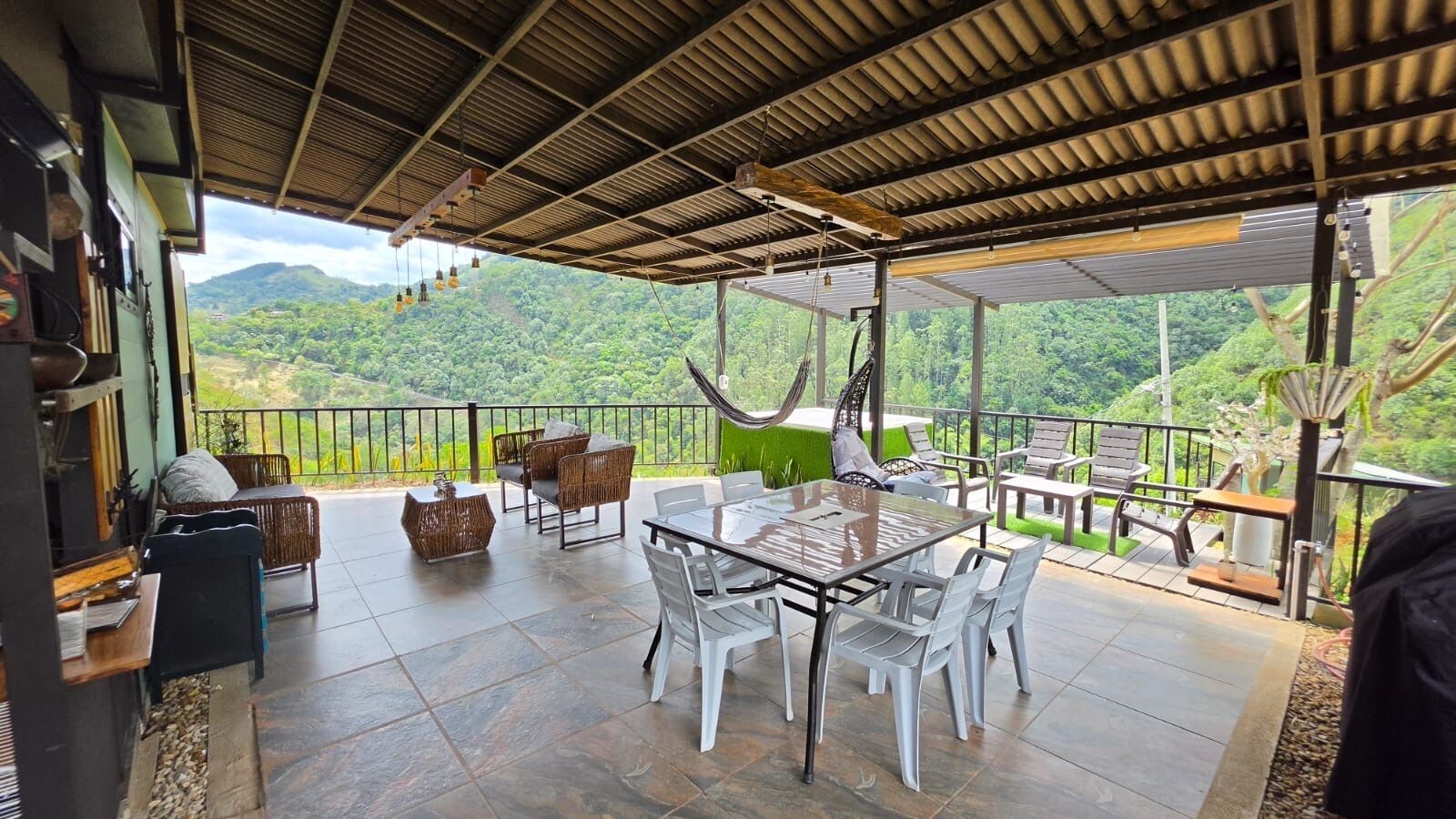 An outdoor patio with a dining table, chairs, and a hammock.