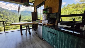 Una cocina con vistas a un paisaje montañoso, una mesa de madera y taburetes de bar.